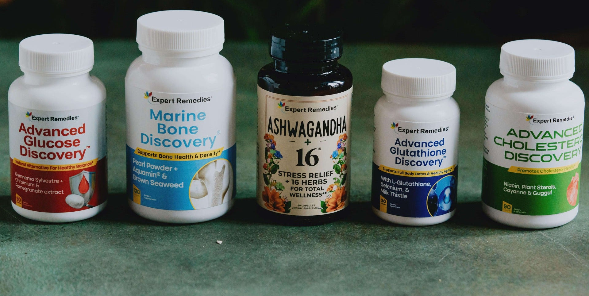 Collection of health supplement bottles on a green surface with a blurred natural background